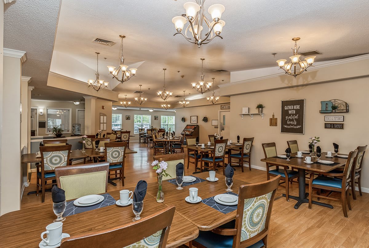 A spacious and elegantly decorated dining room with multiple tables and chandeliers.