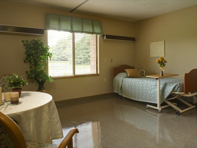 A well-lit hospital room with a single bed, table, and window.