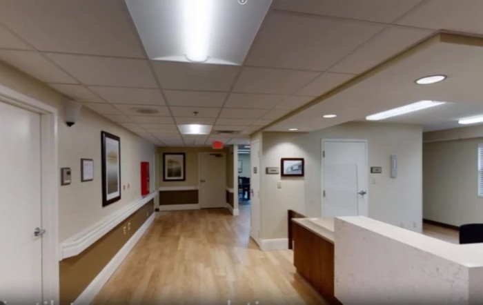 A view of an office hallway with a reception desk and artwork on the walls.