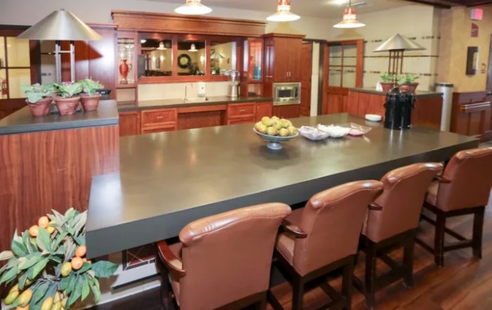 A modern kitchen with a spacious countertop, bar stools, and stylish lighting.