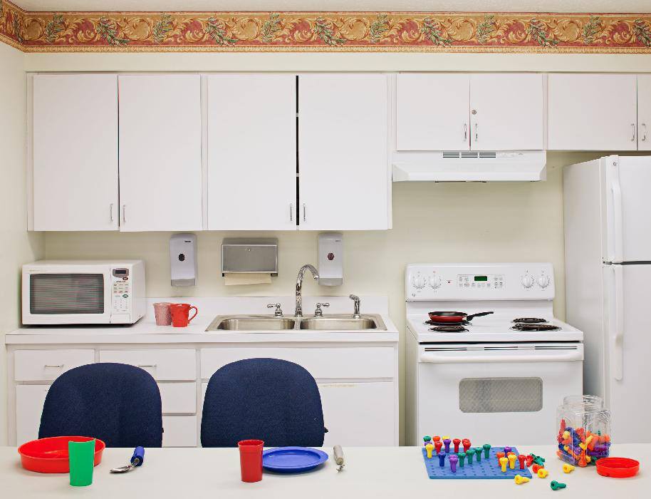 A kitchen setup with cabinets, a sink, microwave, stove, and colorful dishes.