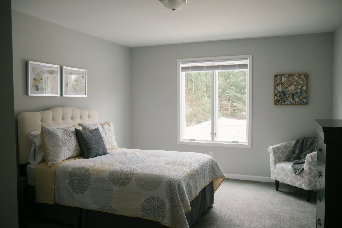 A minimalist bedroom with a neatly made bed and a window offering natural light.