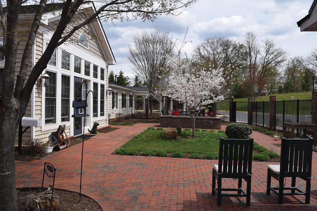 A serene garden with blossoming trees and a brick patio adjacent to a building.