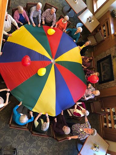 A lively group of senior citizens enjoying a fun parachute activity together.