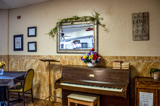 A beautifully arranged corner featuring a classic piano, decorated with a floral arrangement and a framed mirror.
