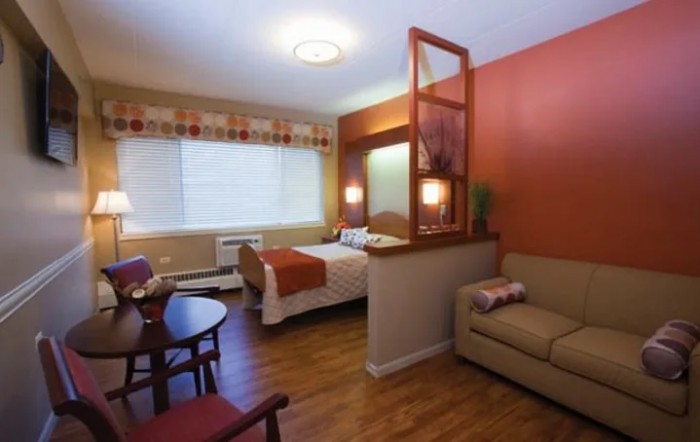 A cozy hotel room with a bed, sofa, and dining area.