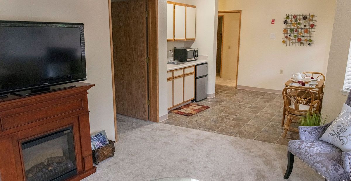A small apartment kitchen with white cabinets and a microwave.