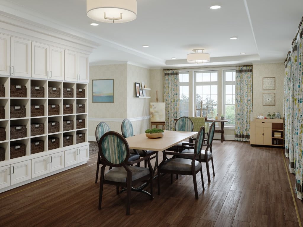 A modern dining room with a large table and upholstered chairs, featuring wooden flooring and ample natural light.