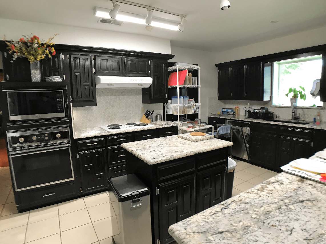 A modern kitchen with dark cabinets and granite countertops.