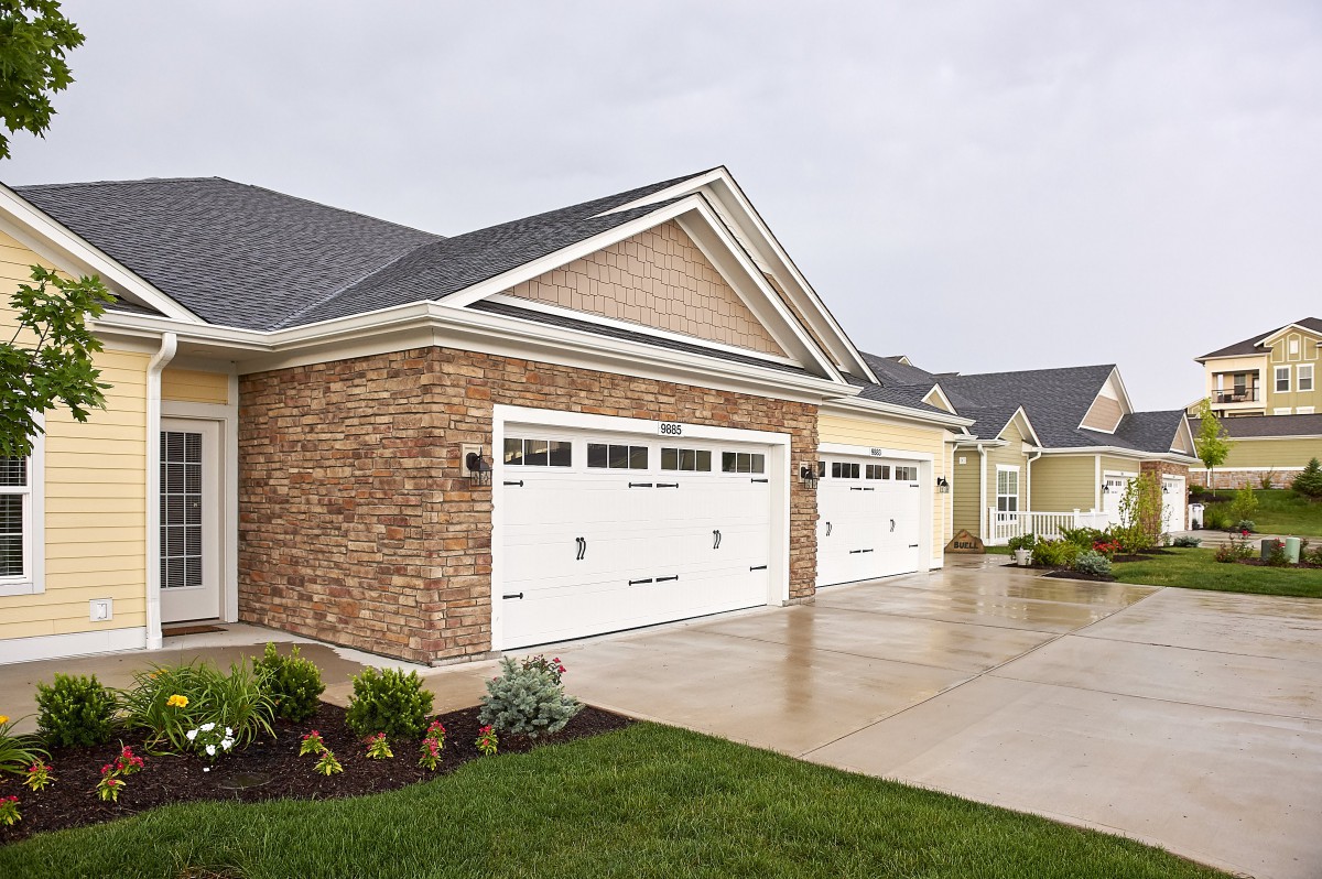 A suburban residential house with a double garage and brick facade.