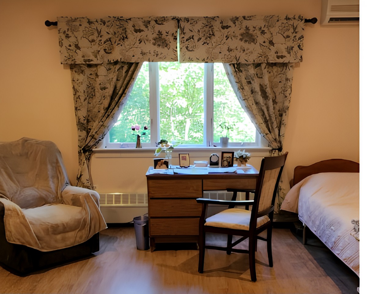 A cozy bedroom with floral curtains, a desk by the window, and comfortable seating.
