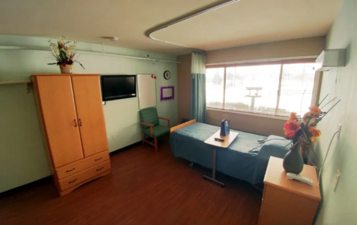 A tidy hospital room with a bed, chair, and window.