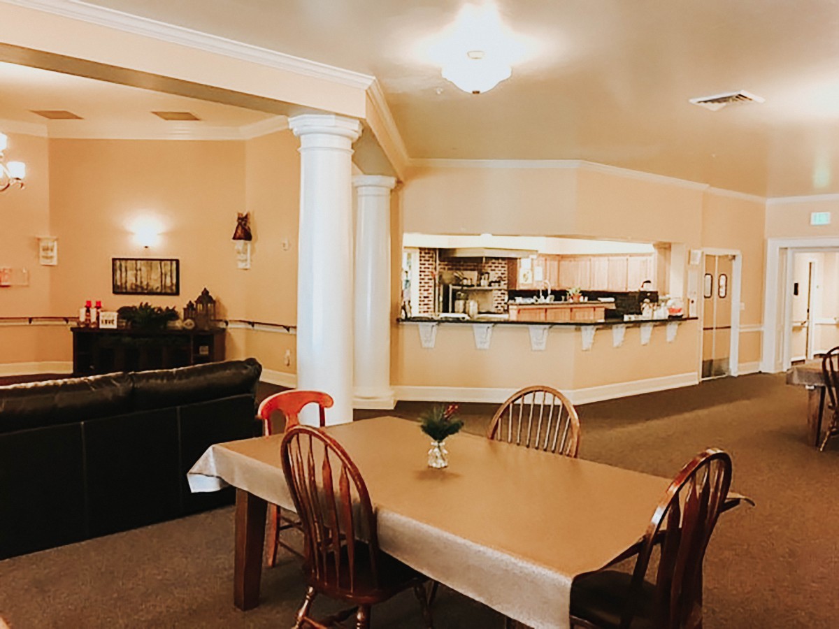 A cozy interior space featuring a dining table with chairs, a sofa in the living area, and an open kitchen.