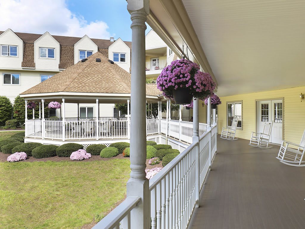 A charming veranda with hanging flower baskets overlooking a beautifully landscaped garden.
