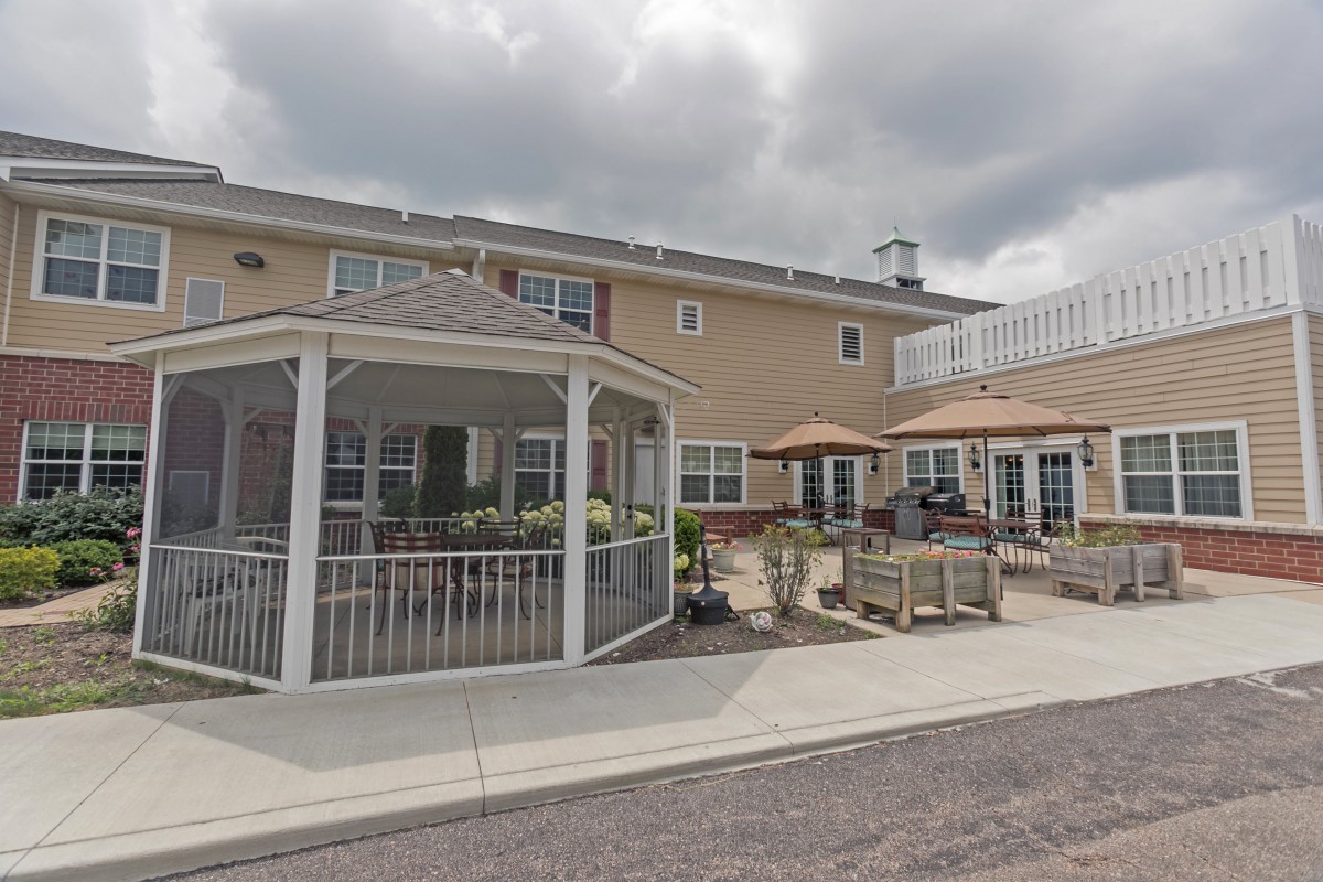 A two-story building with a patio and gazebo under a cloudy sky.