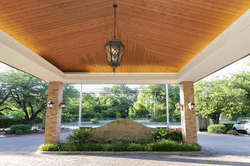 A beautifully designed entrance with a wooden ceiling and elegant lighting, surrounded by lush landscaping.