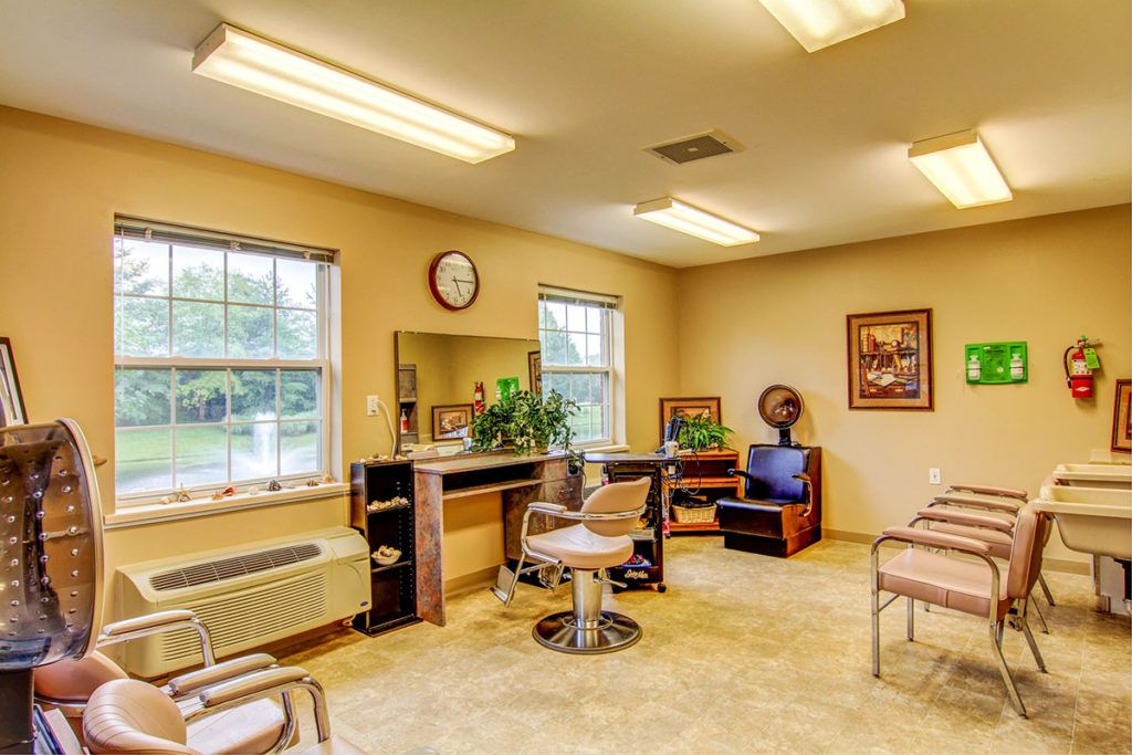 A cozy hair salon interior with chairs, a mirror, and natural light from the windows.