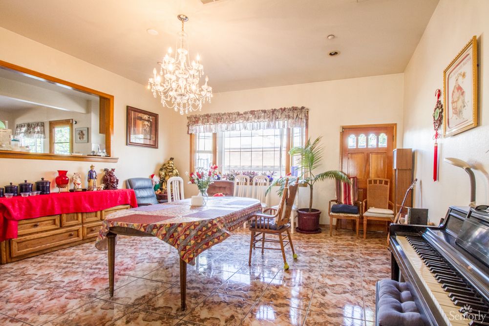 A traditionally decorated dining room with a chandelier and a large table surrounded by chairs.