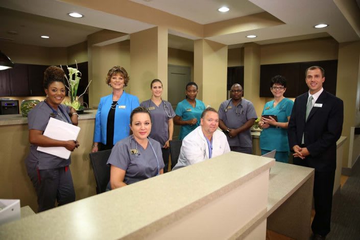 A team of healthcare professionals gathered around a reception desk.