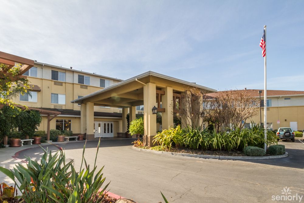 The exterior of a hotel featuring a covered entrance with surrounding greenery.
