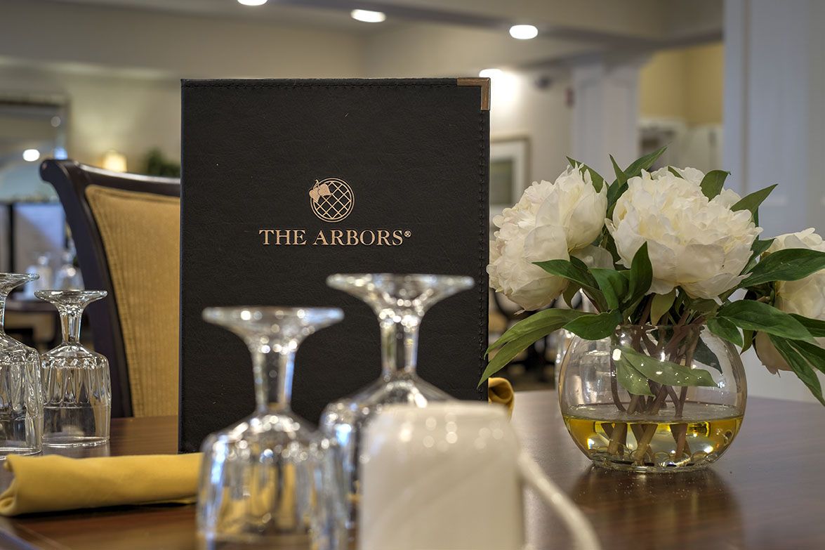 A sophisticated dining table setup with a menu, wine glasses, and a floral arrangement.