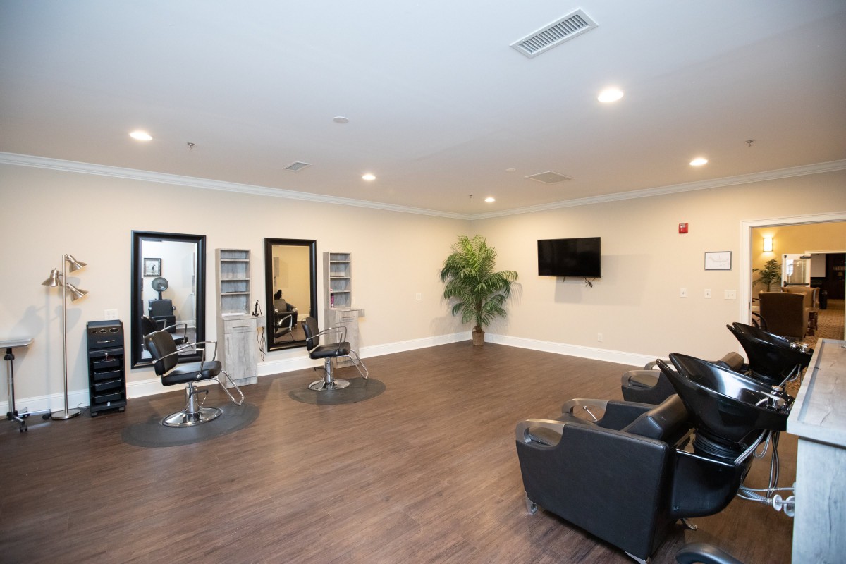 A modern salon interior with chairs, mirrors, and a TV on a wooden floor.