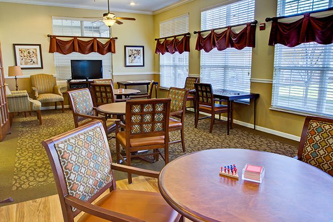 A cozy dining area with multiple tables and chairs, illuminated by natural light coming through large windows.