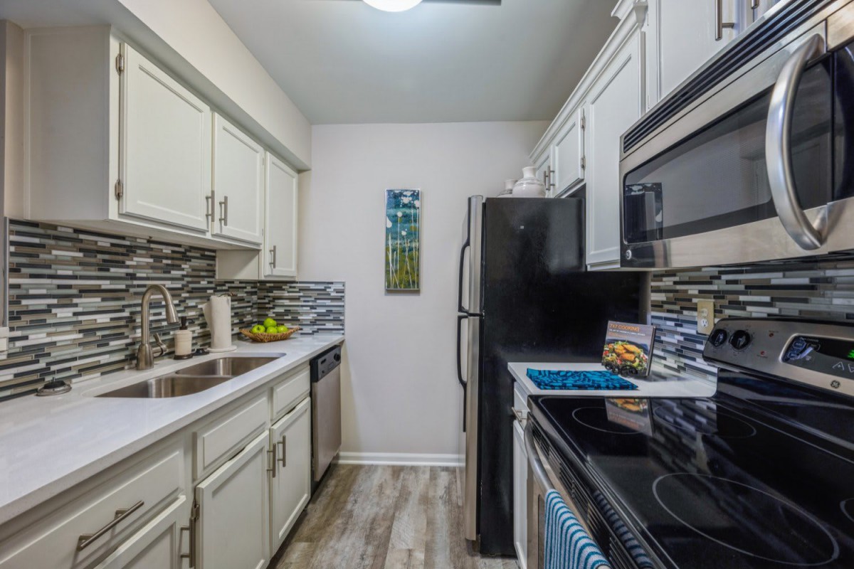 Modern galley kitchen with white cabinets and stainless steel appliances.