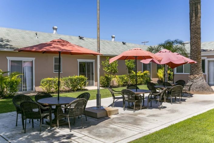 A pleasant outdoor seating area with tables and umbrellas, set in a landscaped garden.