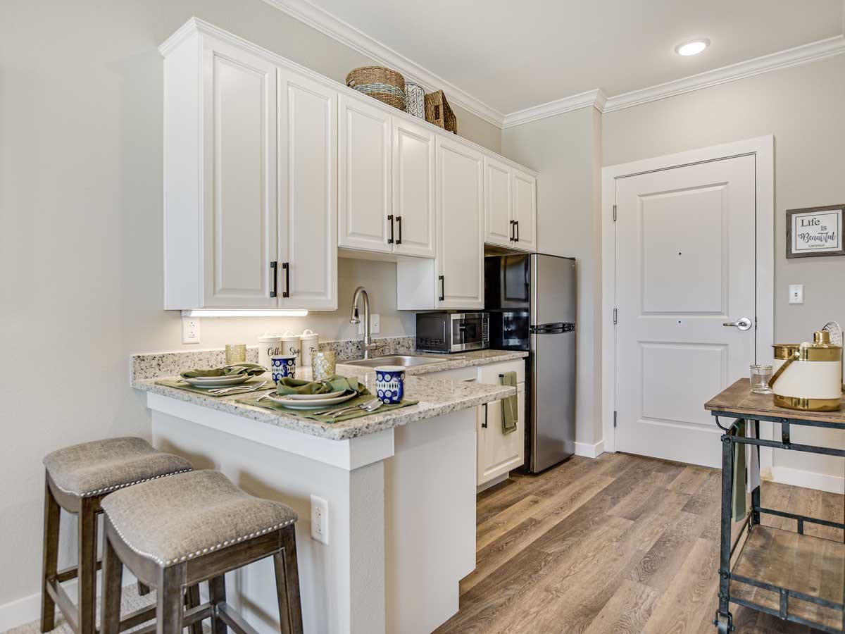A modern kitchen with white cabinets and a breakfast bar with stools.