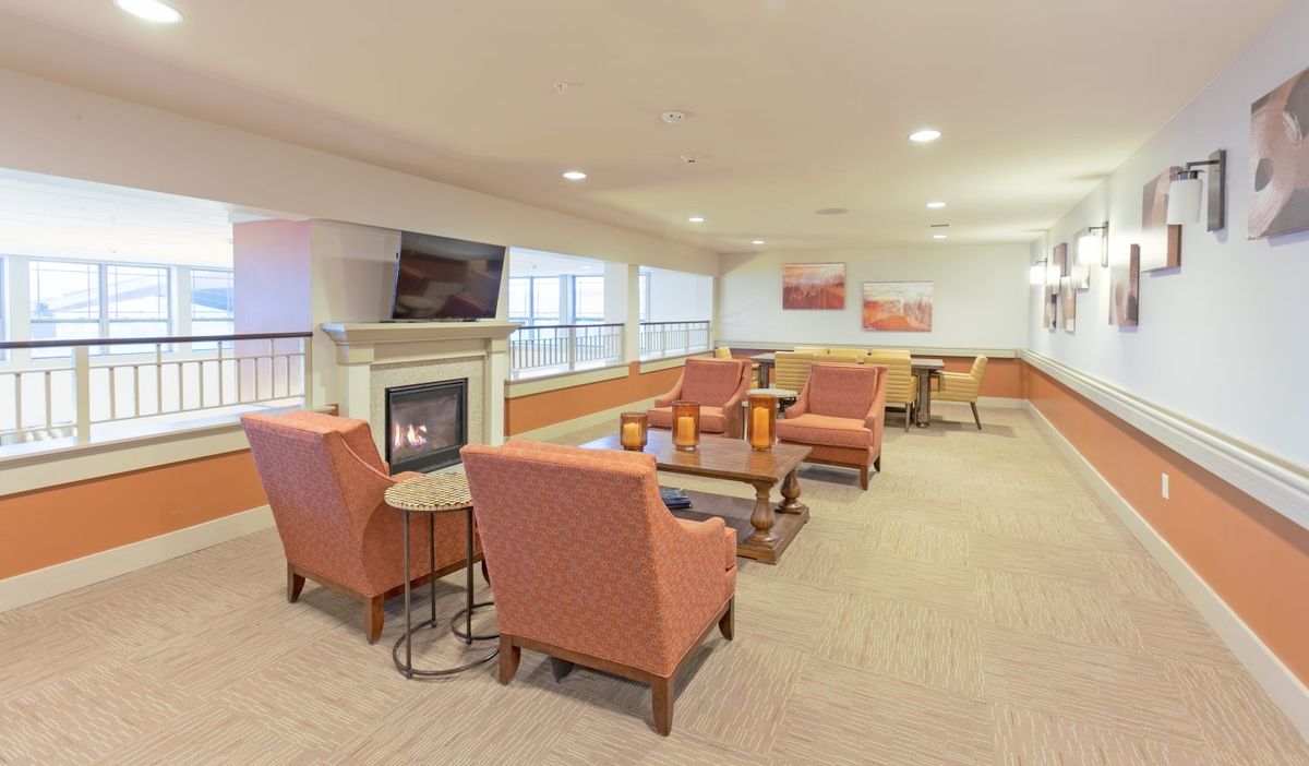 A cozy indoor lounge with comfortable seating, a central fireplace, and a television.