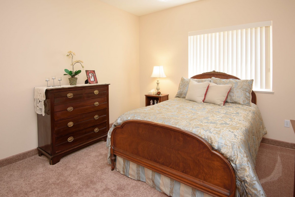A cozy bedroom with a wooden bed, matching dresser, and soft lighting.
