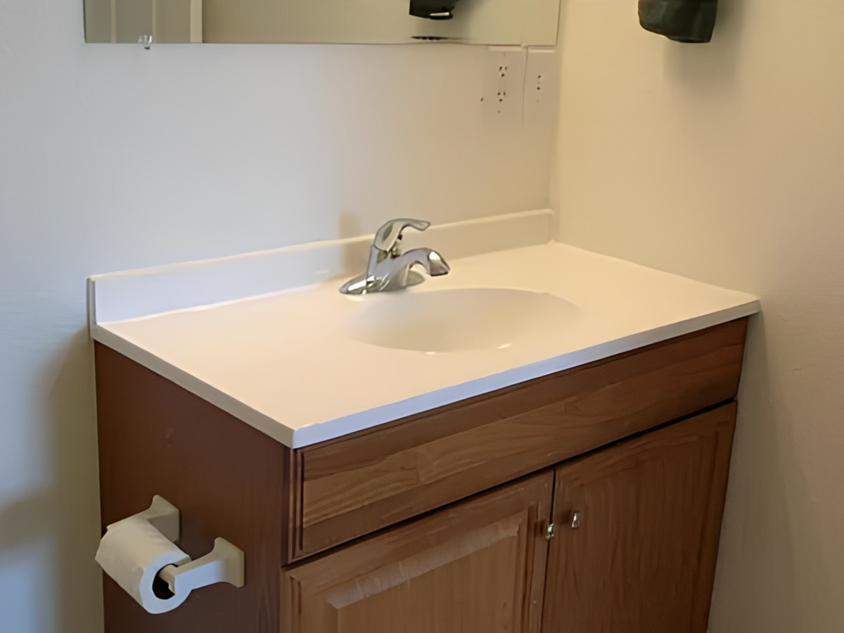A bathroom vanity with a sink, faucet, and mirror above.