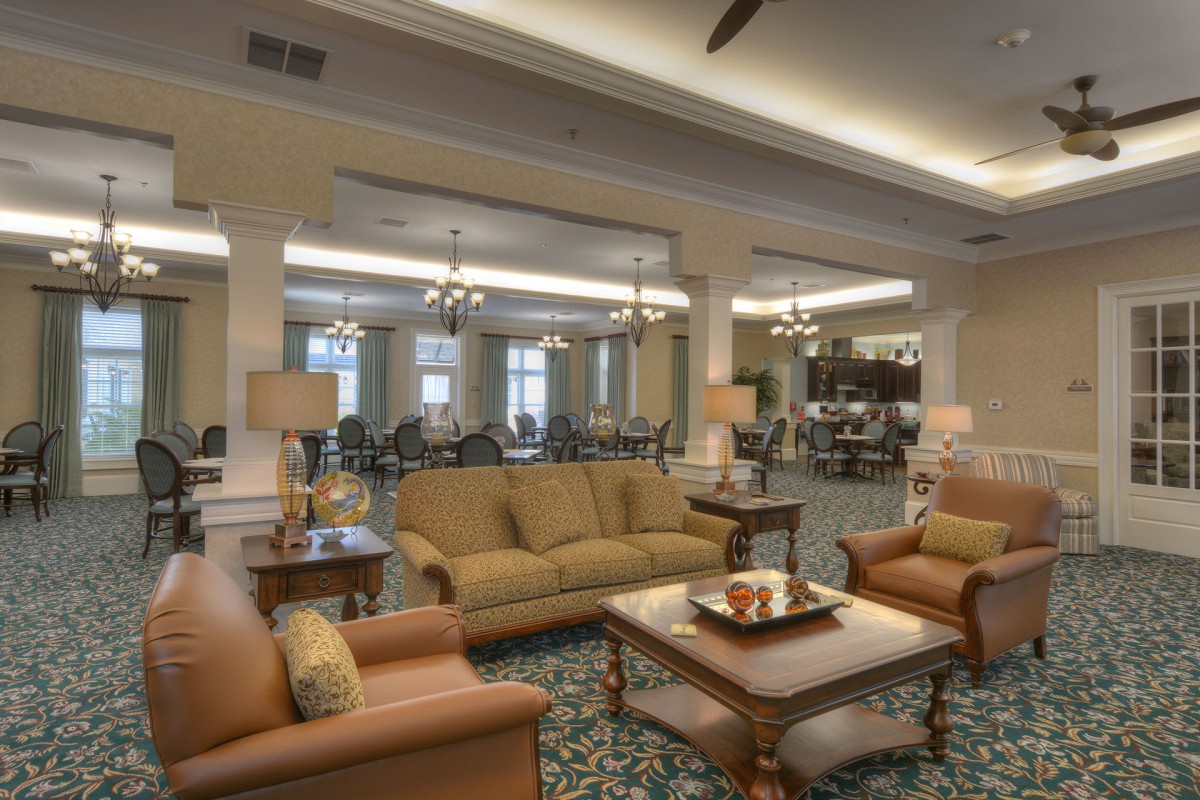 A cozy lobby area with sofas, armchairs, and a coffee table, elegantly lit by chandeliers.