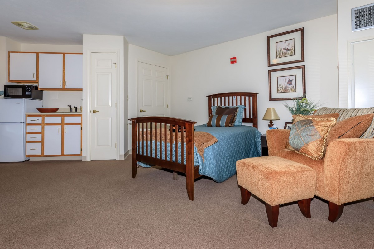 A cozy bedroom with a wooden bed, upholstered chair, and decorative elements.