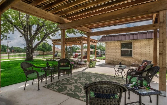 A cozy backyard patio featuring a pergola, comfortable seating, and lush landscaping.