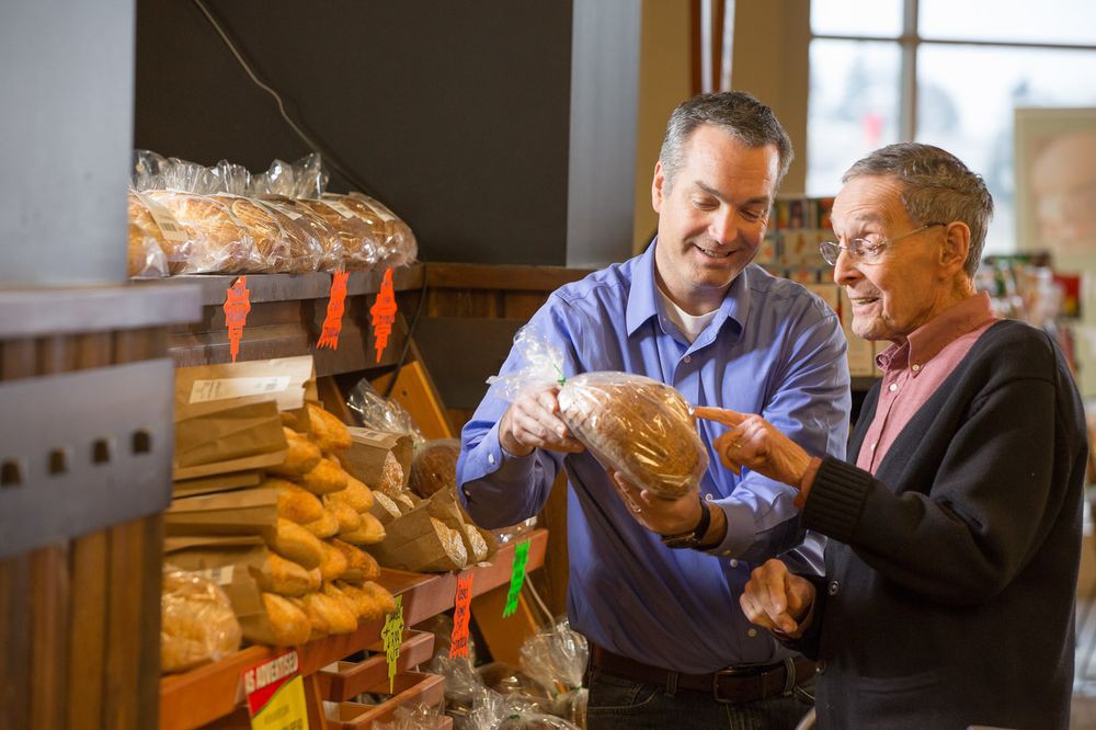 Two men shopping for bread in a bakery.