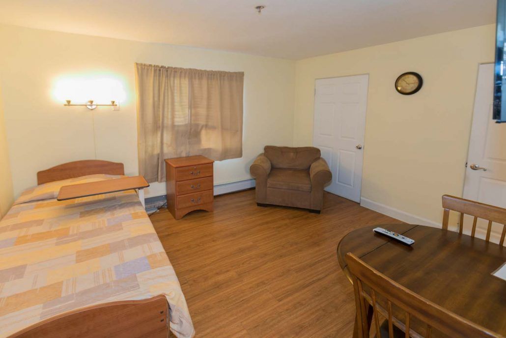 A cozy living room with an armchair, wooden floors, and simple decor.