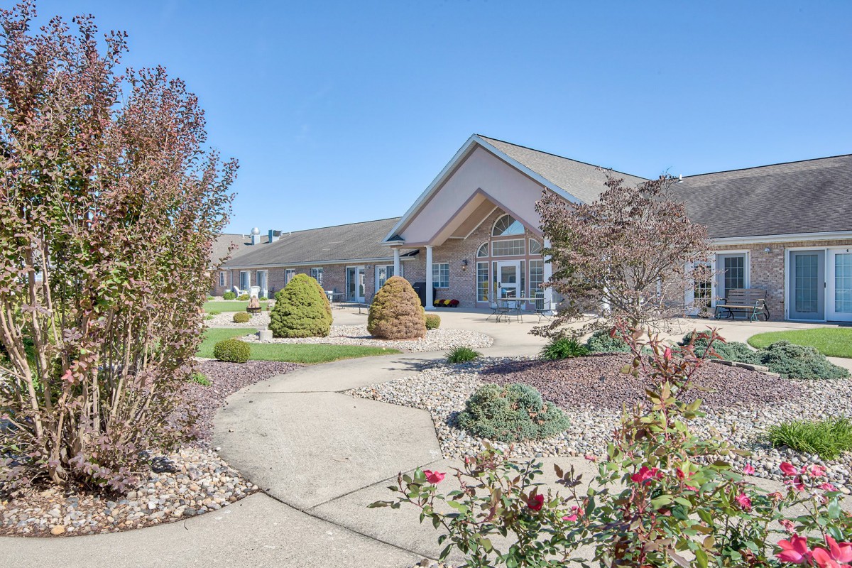 A well-maintained building with landscaped pathways and gardens under a clear blue sky.