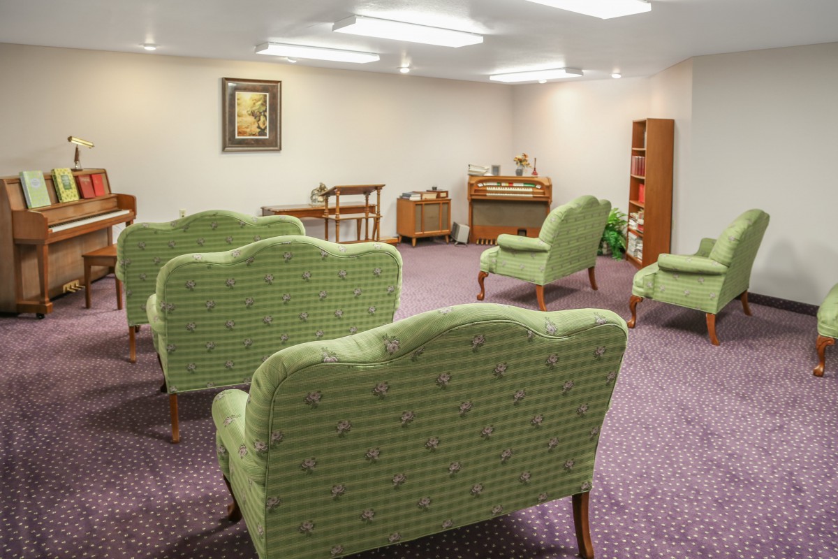 A well-arranged waiting room featuring green upholstered chairs and soft lighting.
