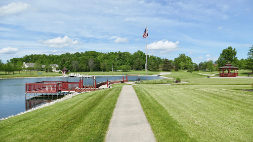 A serene pathway leading towards a picturesque waterfront, adorned with a flag and surrounded by lush greenery.