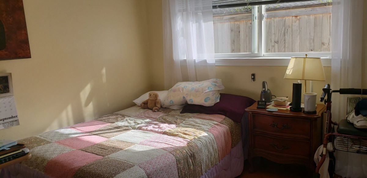 A cozy bedroom with a bed, pillows, and a quilt by the window.