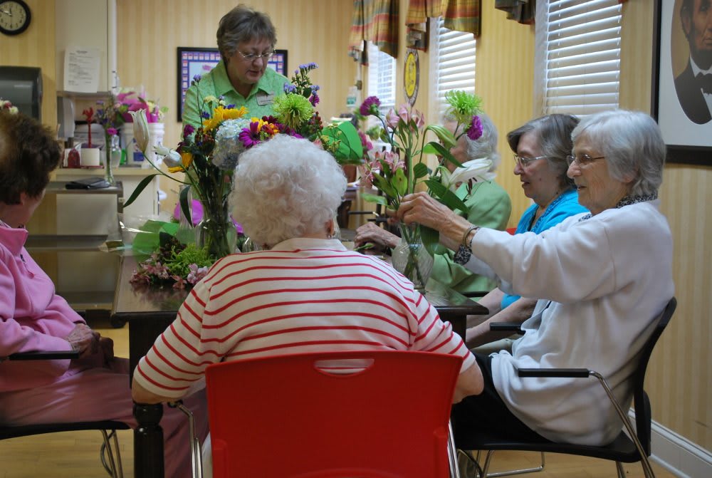 A group of elderly individuals participating in a flower arranging activity indoors.