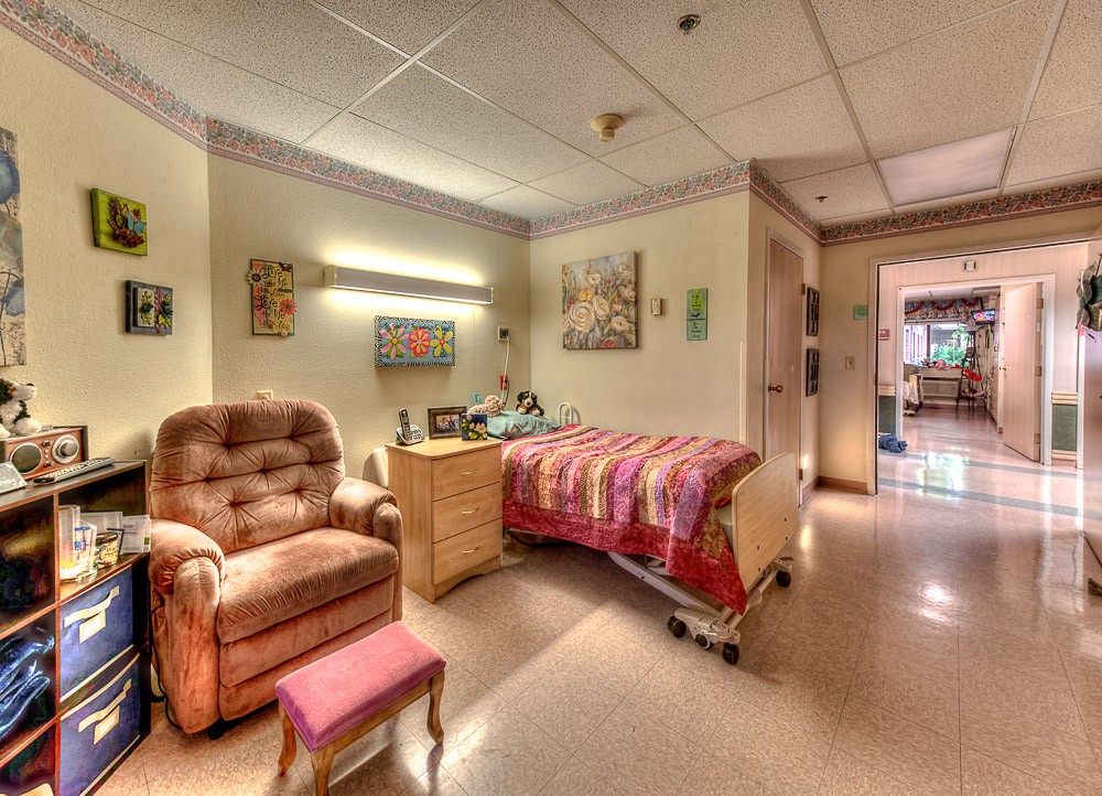 A cozy hospital room with a comfortable chair and a decorated wall.