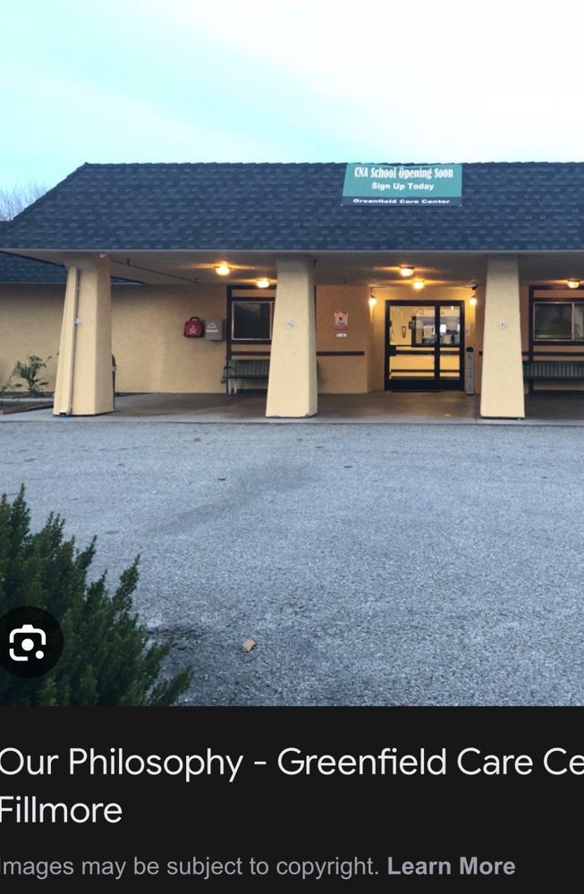 A small building with an entrance lit up in the evening, featuring a spacious parking lot.