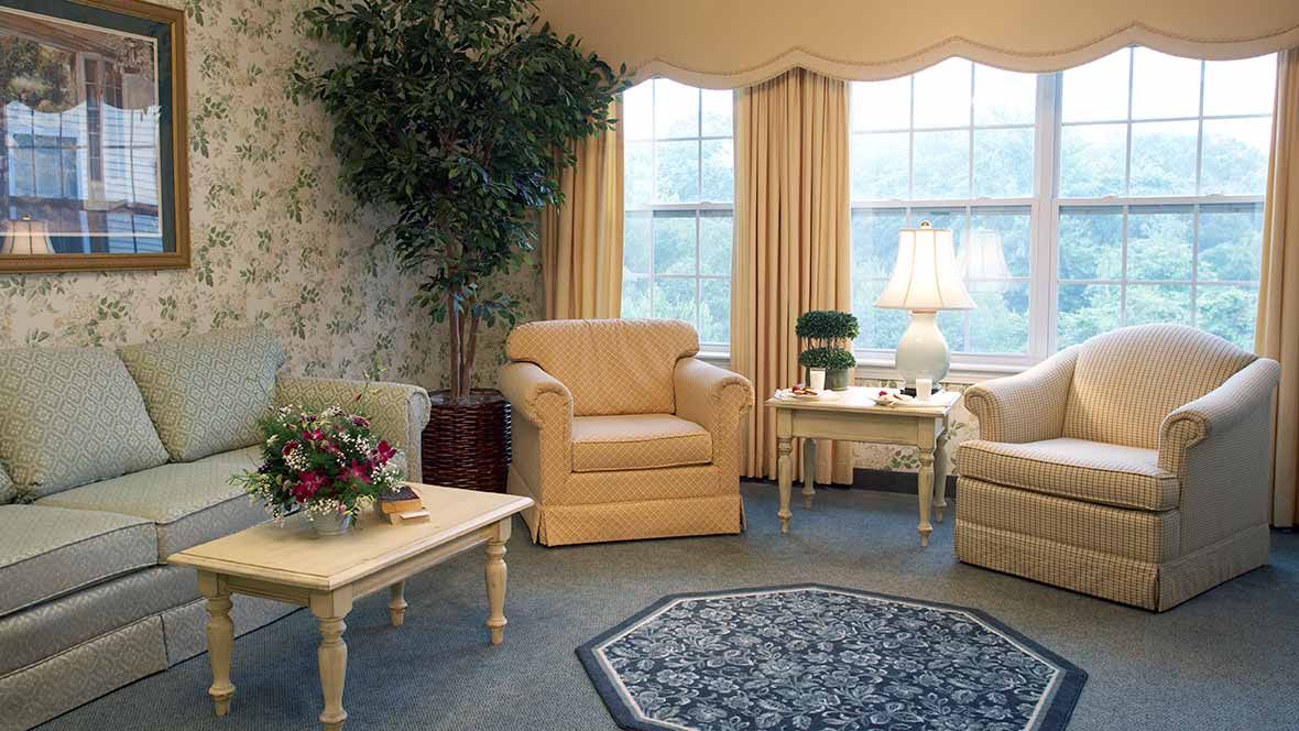 A cozy living room with beige armchairs, a coffee table, and warm lighting.