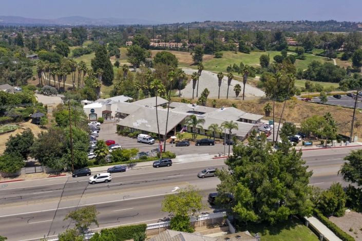 Aerial view of a suburban area with buildings and a road lined with trees.