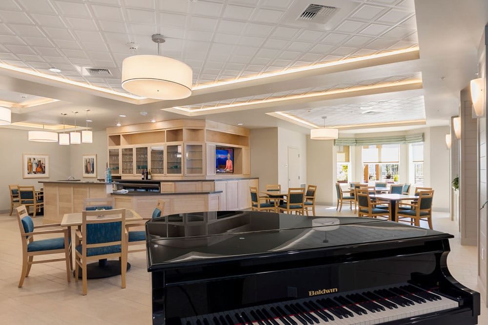 A modern lounge area featuring a grand piano and a bar with ample seating.