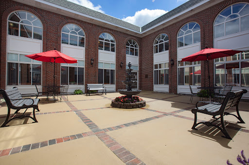 A beautifully designed courtyard with a central fountain surrounded by outdoor seating and red umbrellas.