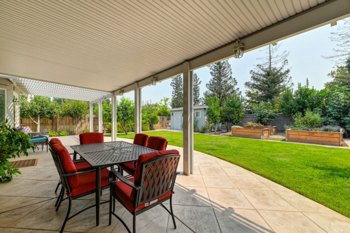 A covered patio with outdoor seating overlooking a well-maintained backyard.